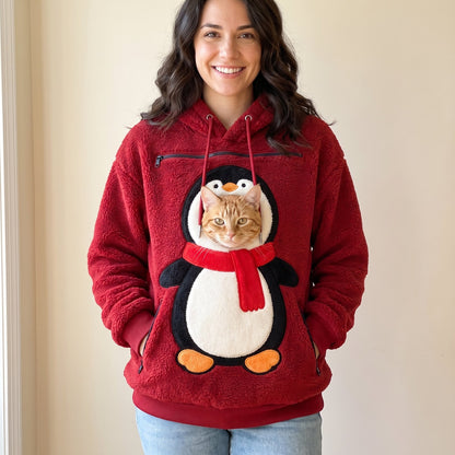 Woman wearing the red Penguin pet pouch hoodie with a cat peeking out of the front pouch