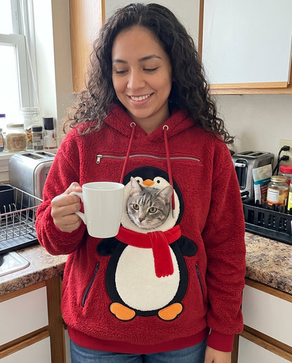 Customer in the Penguin pet pouch hoodie with her cat, holding a mug in the kitchen